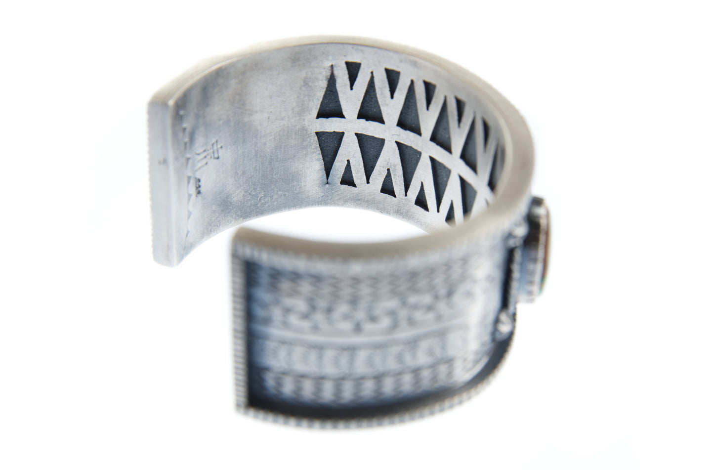 This view shows the interior of the sterling silver stamped overlay braclet. It features the artist's hallmark, as well as the overlay pattern inspired by Native American pottery designs. 